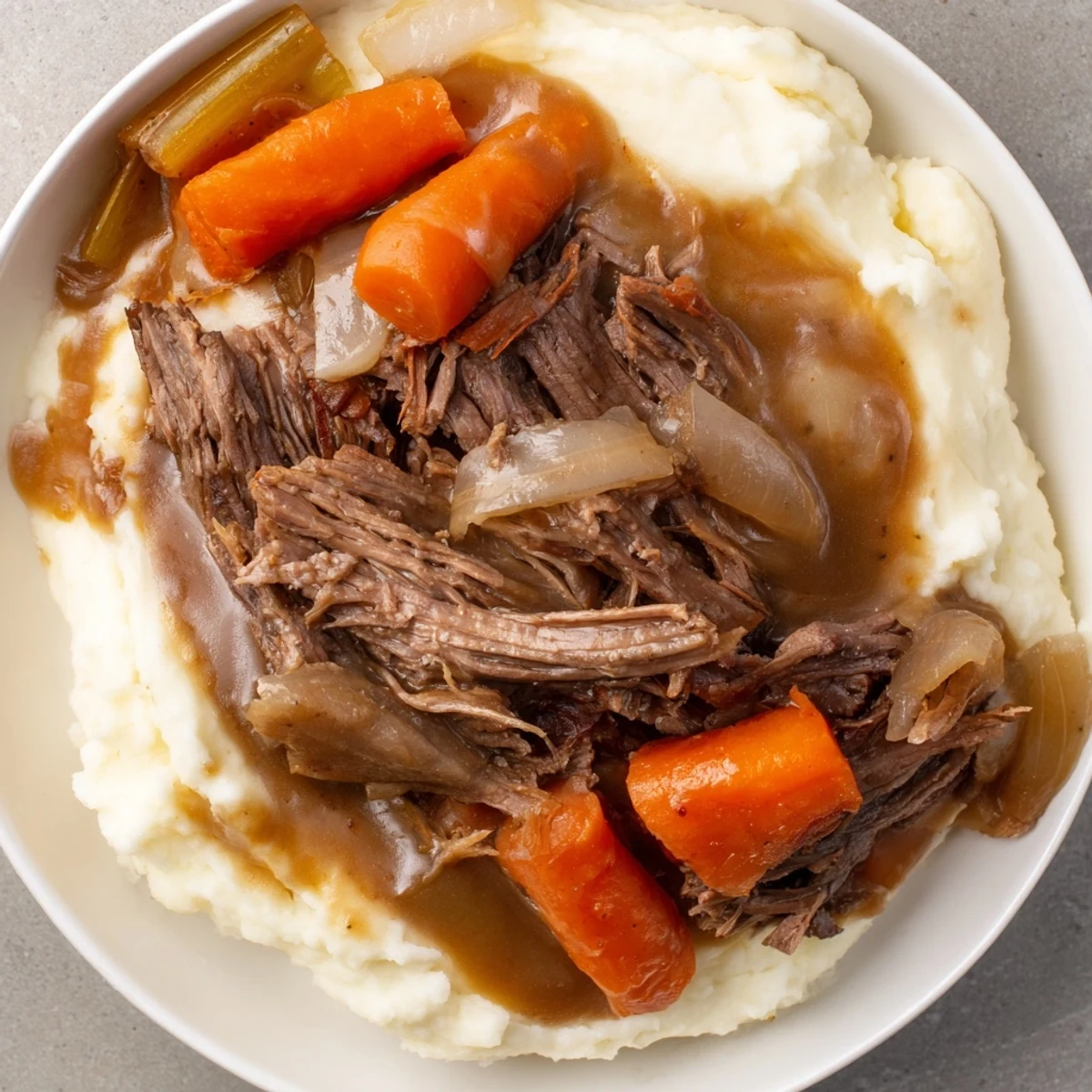 Tender Slow Cooker Pot Roast with vegetables and rich gravy, served over fluffy mashed potatoes.
