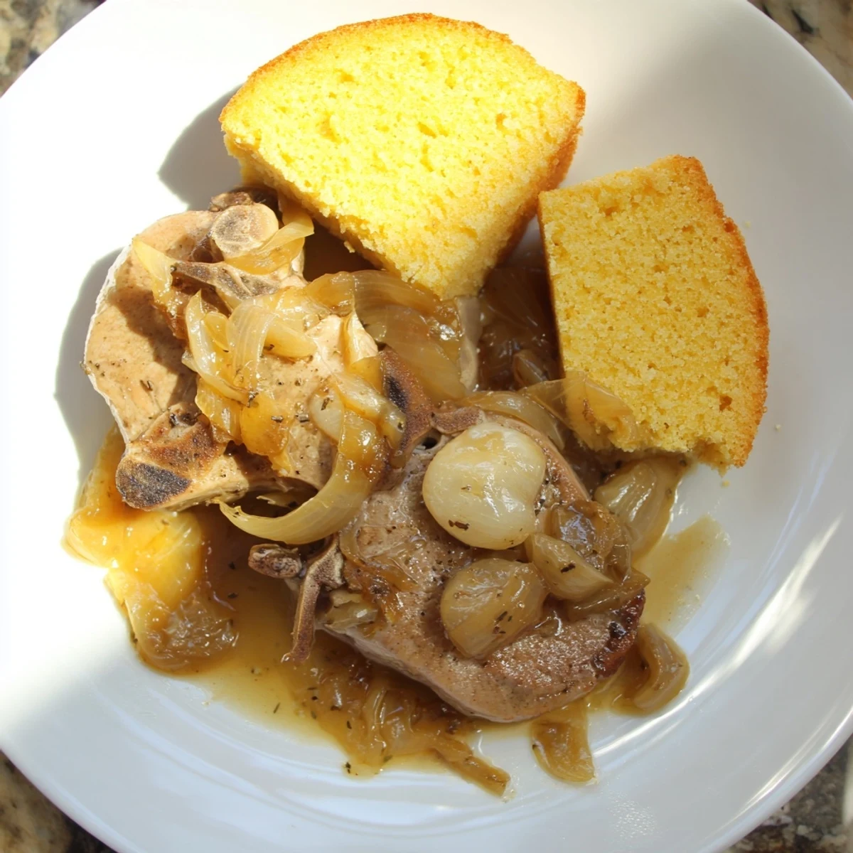 Golden, crusty cornbread beside savory, tender smothered pork chops swimming in rich gravy.