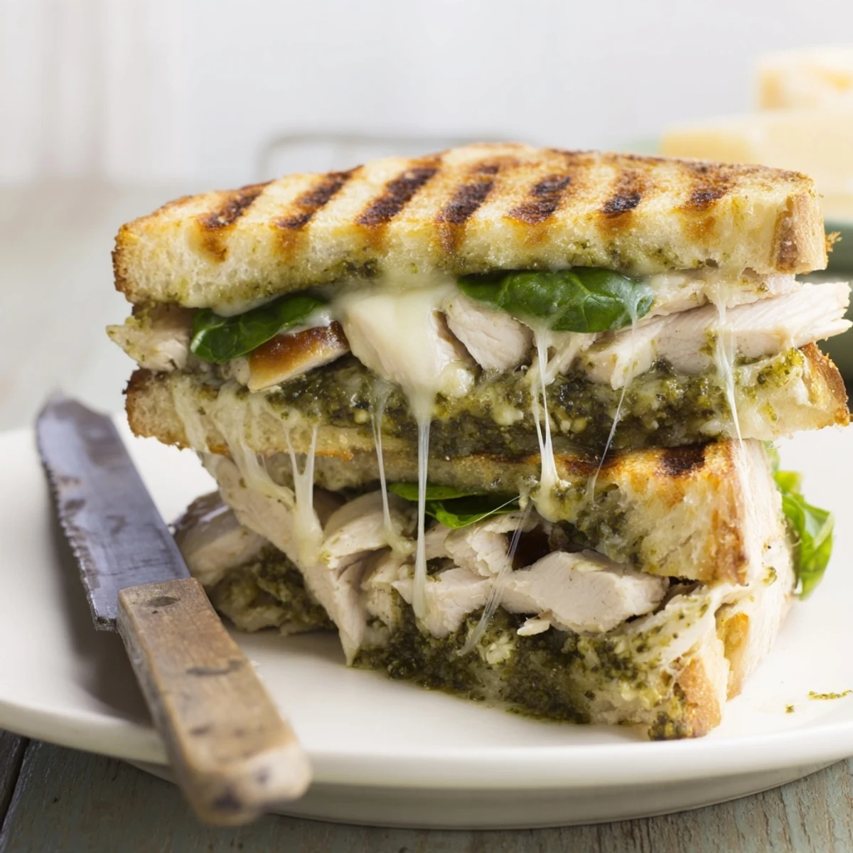 A warm, handheld Chicken Pesto Panini pressed to perfection, ready to be dipped in balsamic glaze.