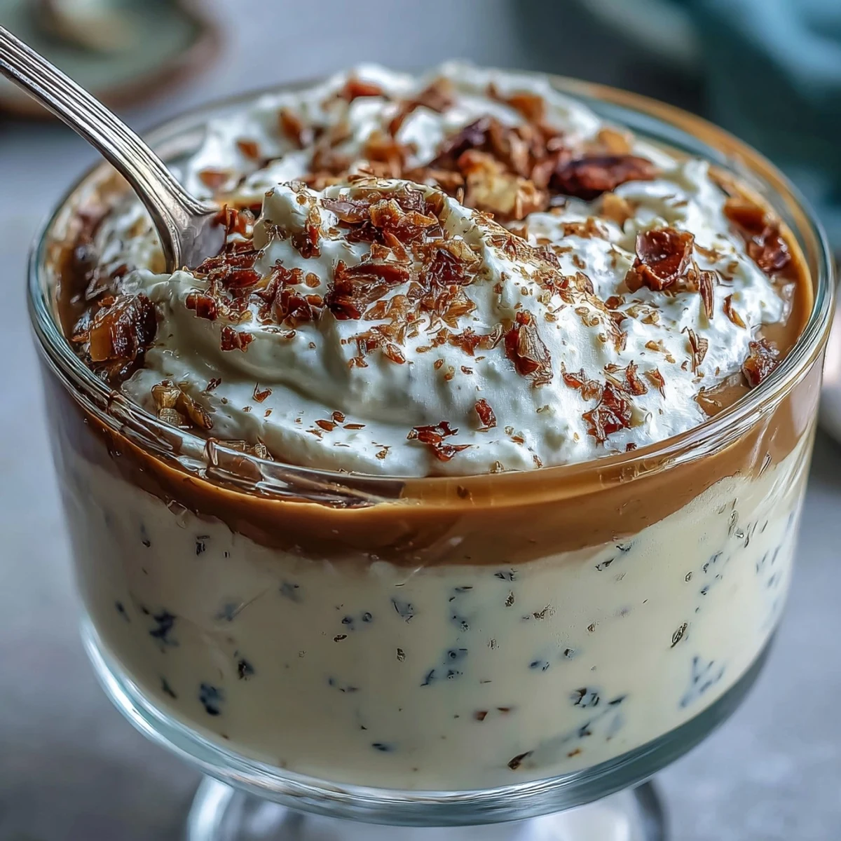 Chilled Hojicha Pudding topped with whipped cream and cocoa powder in a glass.