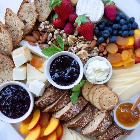 Colorful jam-infused brunch board overflowing with fresh fruits, cheeses, and artisan breads.