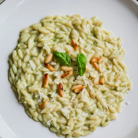 Steaming bowl of 15-Minute Creamy Pesto Risoni, garnished with fresh basil and toasted pine nuts.
