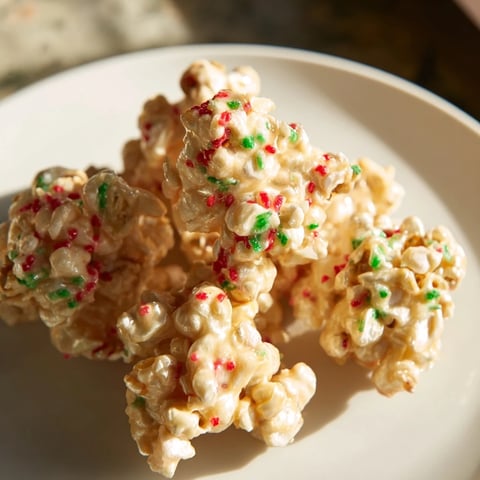 Warm Popcorn Piles scattered with festive red and green sprinkles, a sweet snack ideal for holiday enjoyment.
