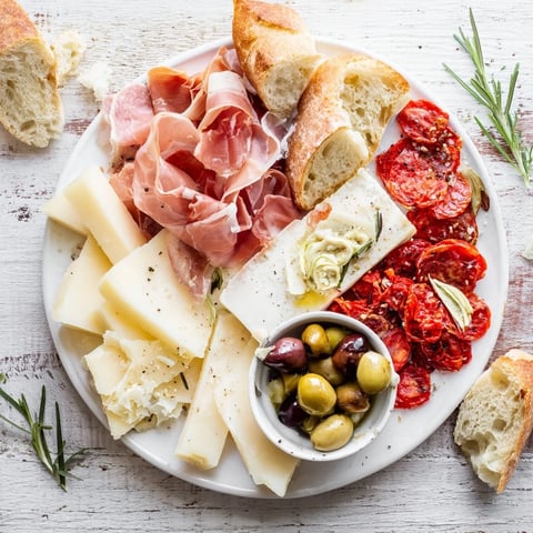 Rustic Italian Farmhouse Board displays a variety of cheeses, meats, bread, olives, and tomatoes, inviting you to enjoy this Italian feast.
