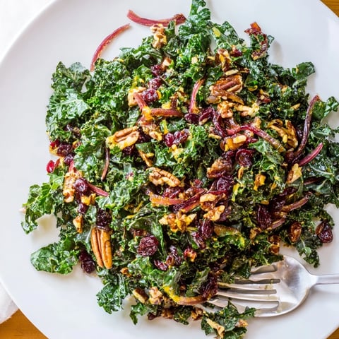 Warm kale salad with maple mustard dressing, toasted nuts, and bright cranberries.
