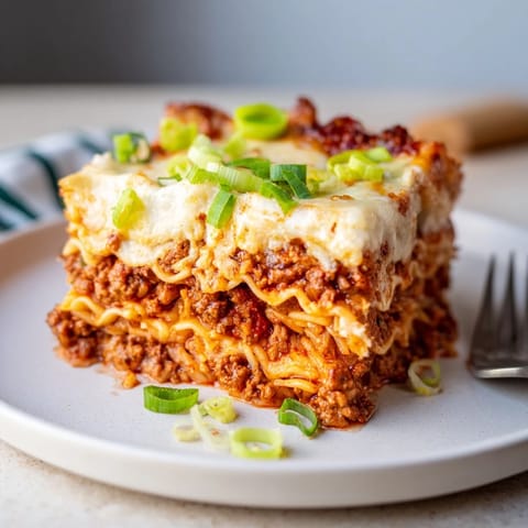 Comforting Spicy Ramen Lasagna topped with melted cheese and a rich tomato sauce.  