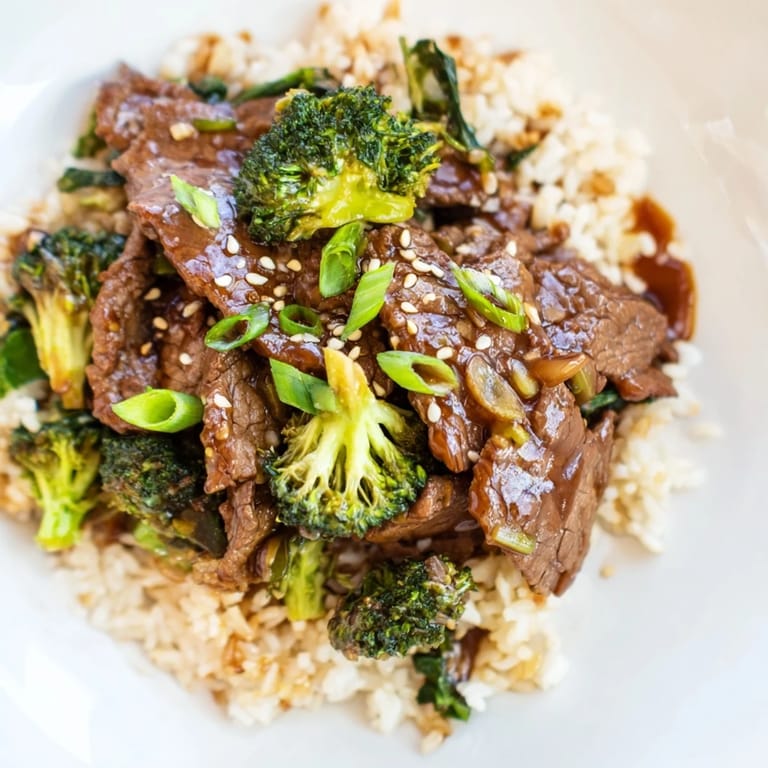 Sizzling slow-cooker Beef & Broccoli with broccoli florets and a rich brown sauce, ready to serve alongside fluffy rice.