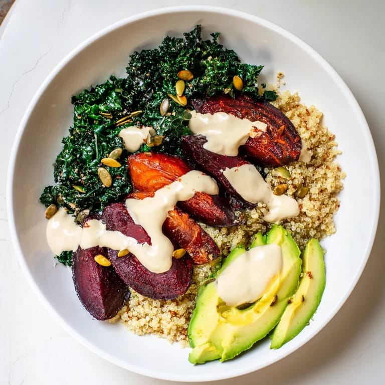 This healthy Quinoa, Kale & Roasted Beet Bowl features creamy tahini dressing drizzled over colorful vegetables ready to enjoy.