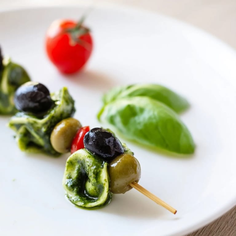 Freshly assembled Appetizer Skewers starring tortellini, pesto, and olives, perfect for summer gatherings.