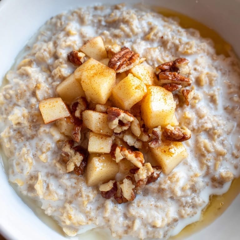 A close-up of a warm apple pie oatmeal breakfast bowl, ready to eat with toasted pecans.