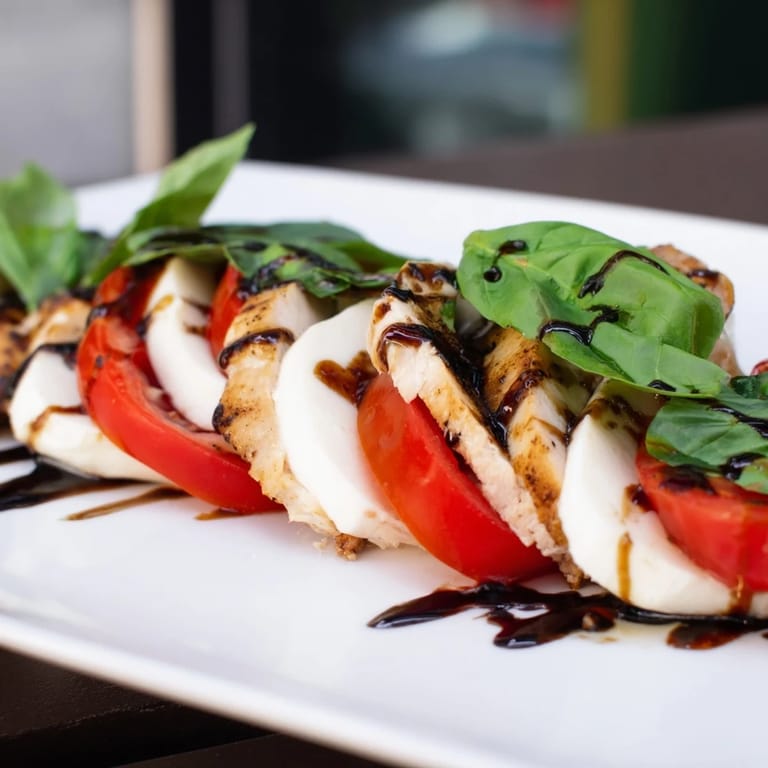 Fresh basil leaves and ripe tomato slices frame tender grilled chicken on this vibrant Chicken Caprese Salad, ready for a light, healthy meal.