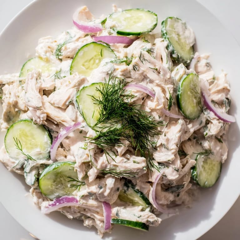 Creamy cucumber chicken salad served in a white bowl, garnished with green onions and lemon wedges, perfect for a refreshing high-protein lunch.